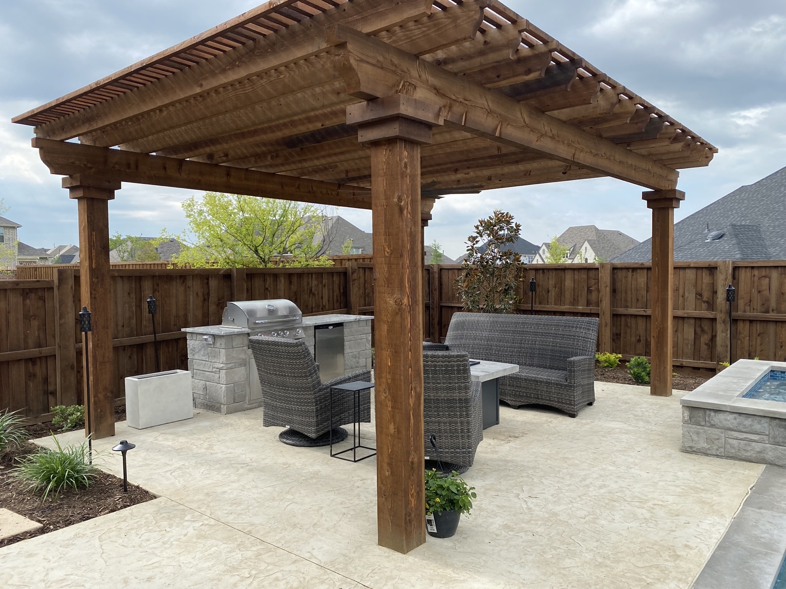 Freshly stained cedar arbor over a stamped concrete patio